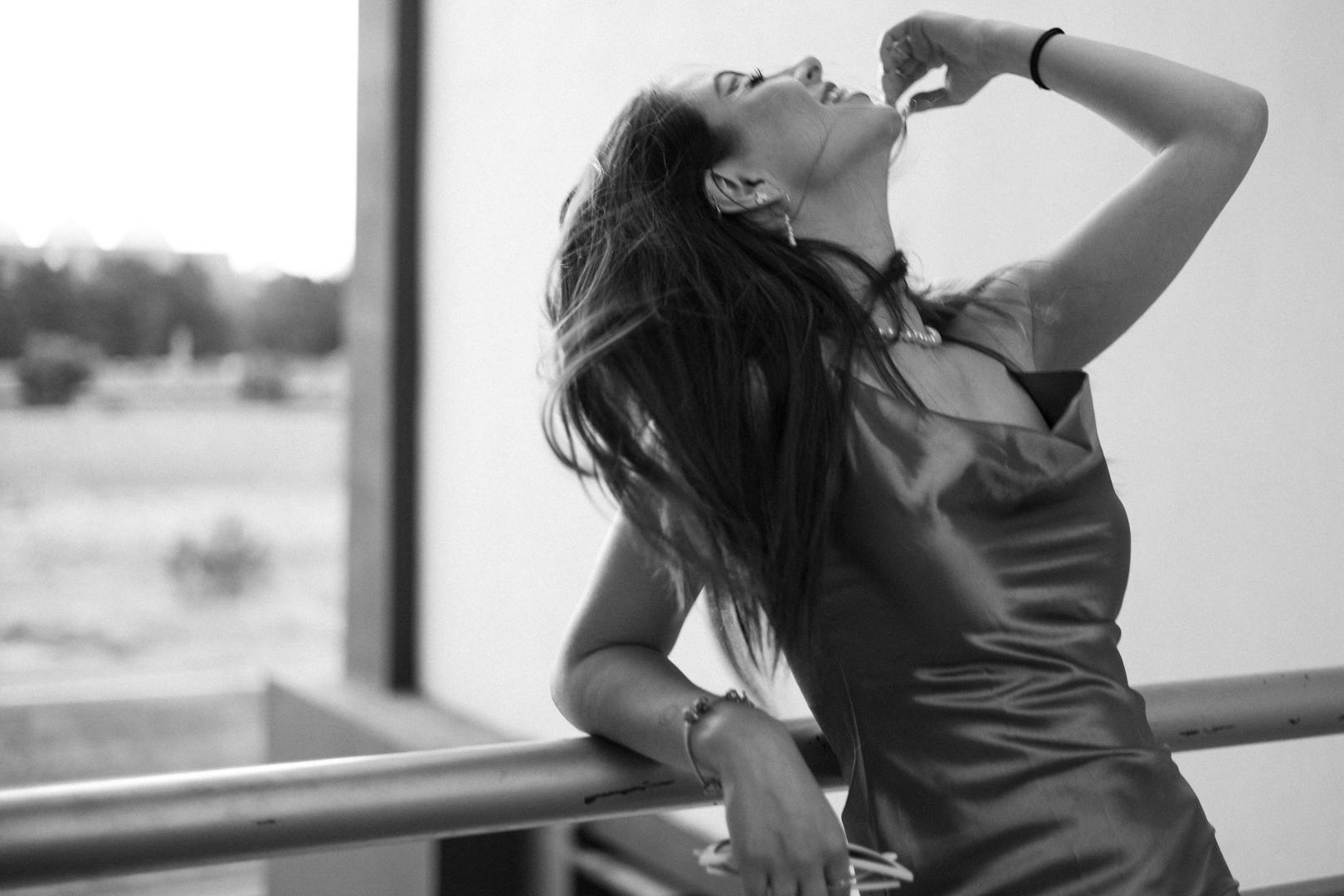 Stylish black and white portrait of a woman in a dress outdoors, exuding elegance and confidence.